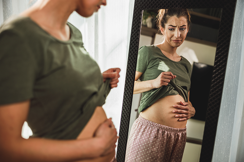 bloated woman looking in mirror