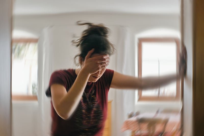 A woman holds her head, the room appears to be spinning.